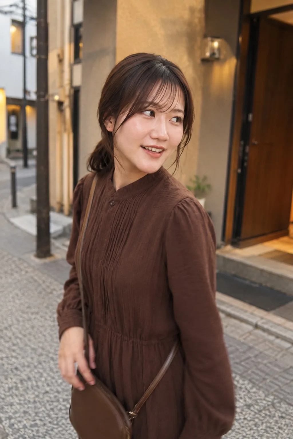 古い建物の並ぶ街路で茶色のワンピースを着て横を見ながら笑う人物