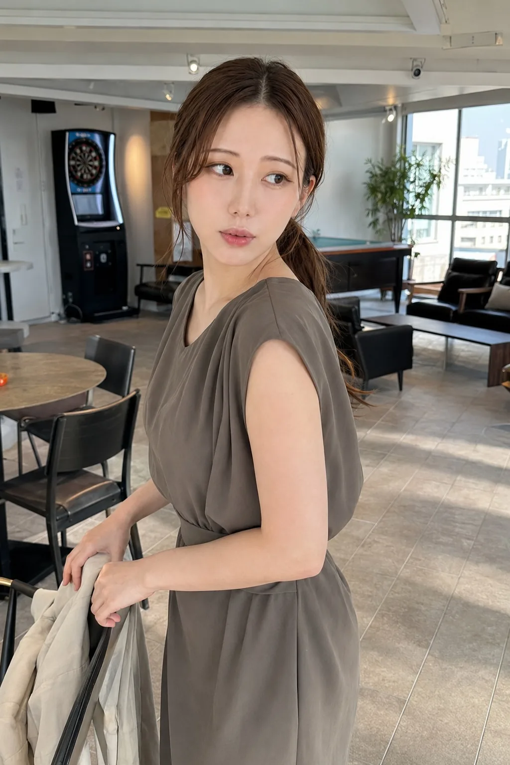 明るい店内で淡い茶色のノースリーブワンピースを着て横を見る人物