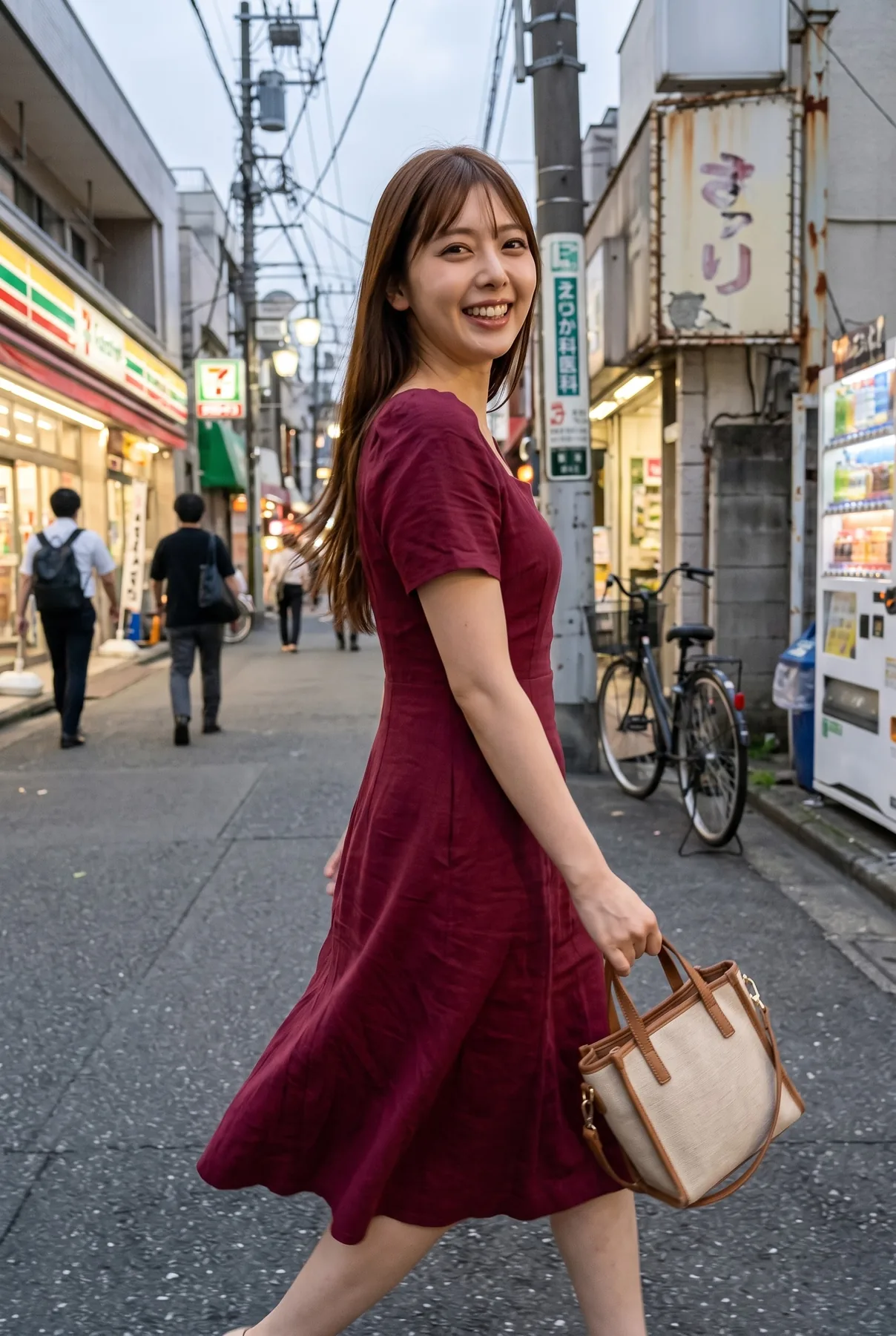 店舗の並ぶ街路で赤紫色の半袖ワンピースを着てバッグを持ち歩きながら笑う人物